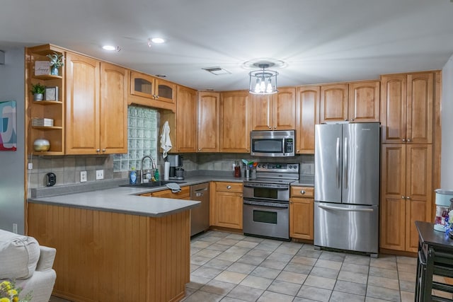 kitchen featuring visible vents, a peninsula, tasteful backsplash, a sink, and stainless steel appliances