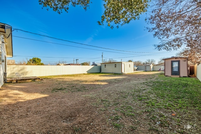 view of yard with a storage shed, a fenced backyard, and an outdoor structure