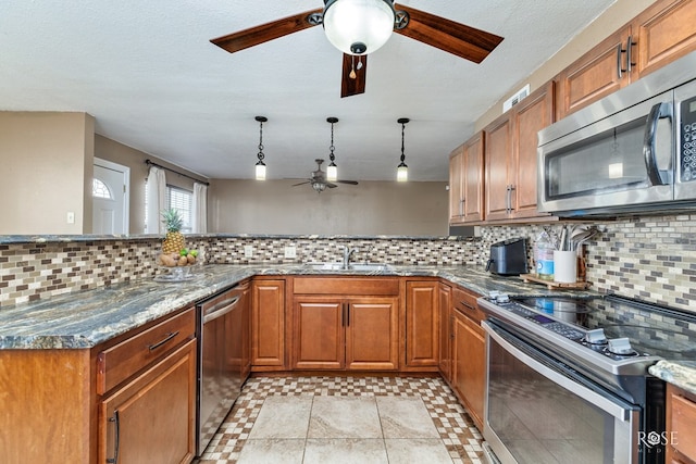 kitchen with stainless steel appliances, brown cabinetry, a sink, and ceiling fan