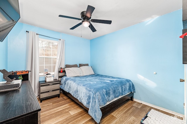 bedroom with light wood-style floors, baseboards, and a ceiling fan