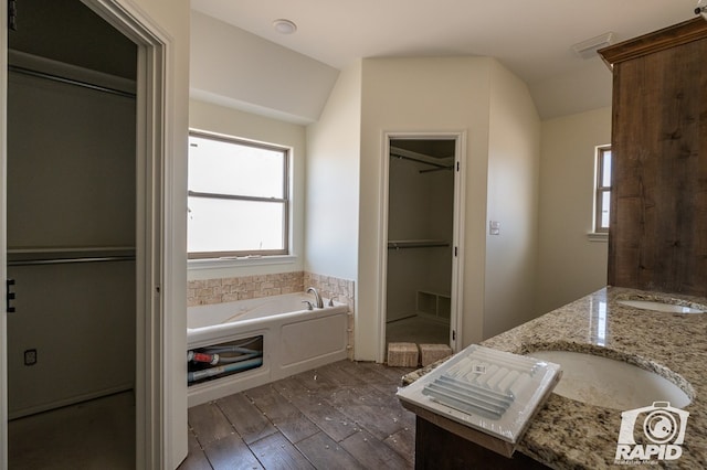 full bathroom with lofted ceiling, a walk in closet, hardwood / wood-style floors, and a bath