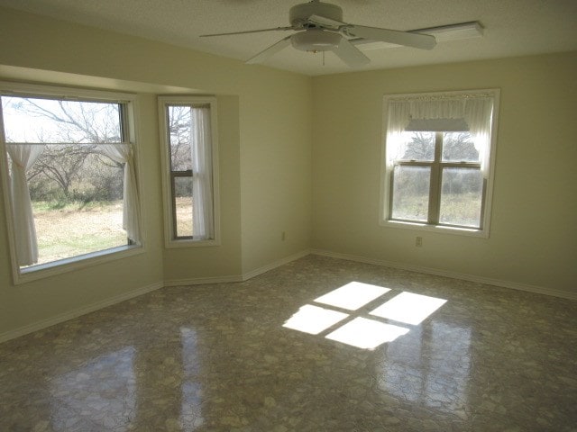 empty room with ceiling fan and plenty of natural light