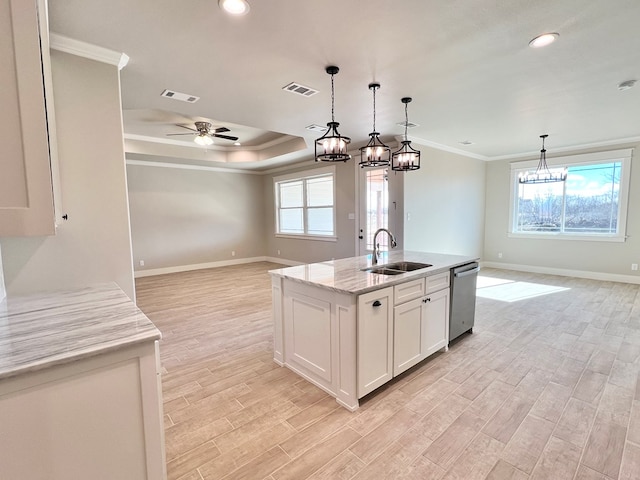 kitchen with pendant lighting, sink, dishwasher, white cabinetry, and an island with sink