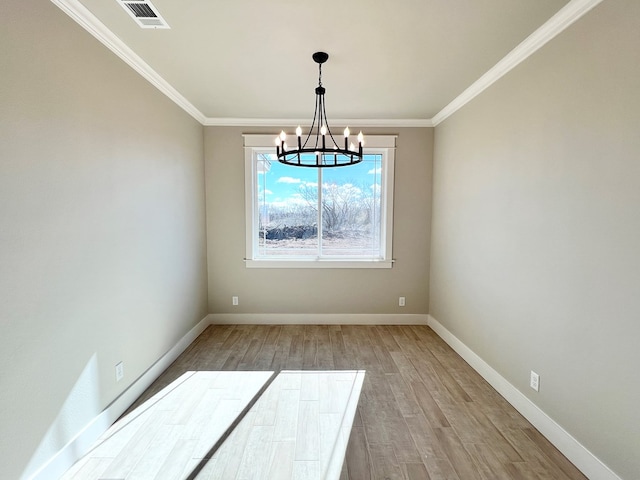 spare room with an inviting chandelier, ornamental molding, and light hardwood / wood-style flooring