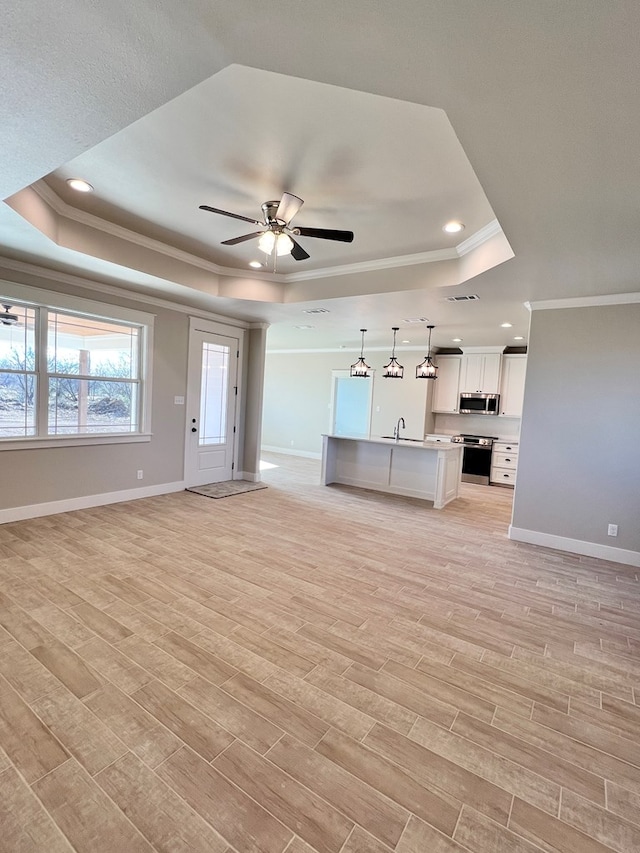 unfurnished living room with crown molding, a raised ceiling, and light hardwood / wood-style flooring