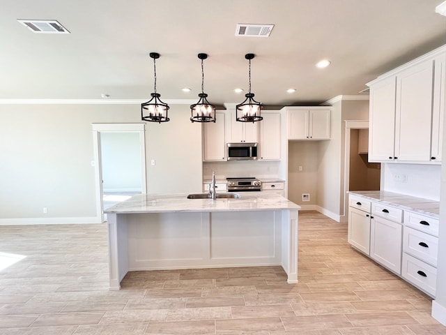 kitchen featuring an island with sink, appliances with stainless steel finishes, sink, and decorative light fixtures