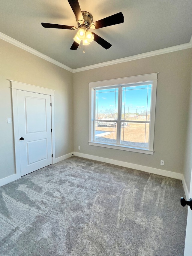 empty room with ceiling fan, ornamental molding, and carpet flooring