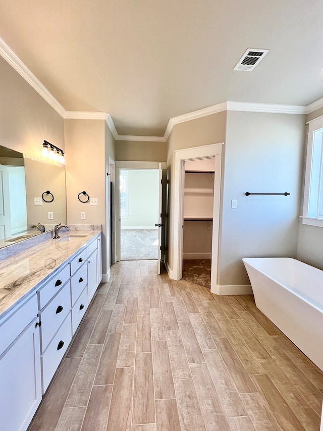 bathroom with vanity, wood-type flooring, ornamental molding, and a bathing tub