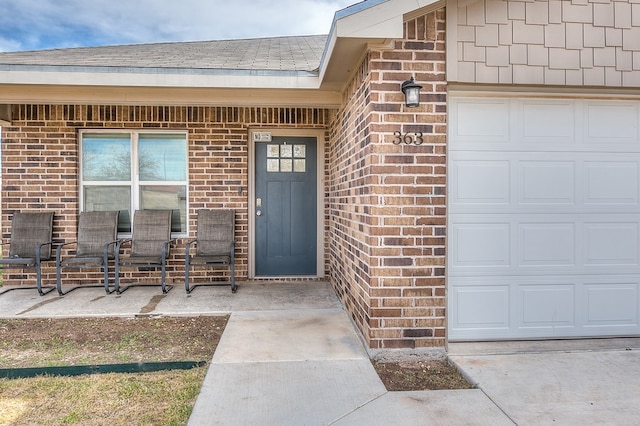 363 E 49th St, San Angelo, TX 76903 - view of exterior entry with brick siding, a garage, and a shingled roof