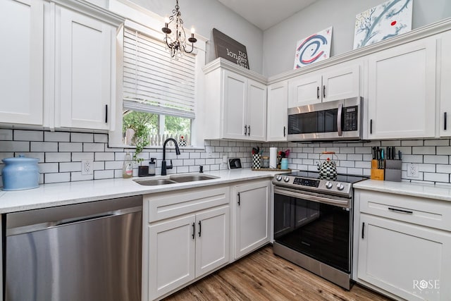 kitchen with white cabinetry, sink, decorative backsplash, light hardwood / wood-style floors, and stainless steel appliances