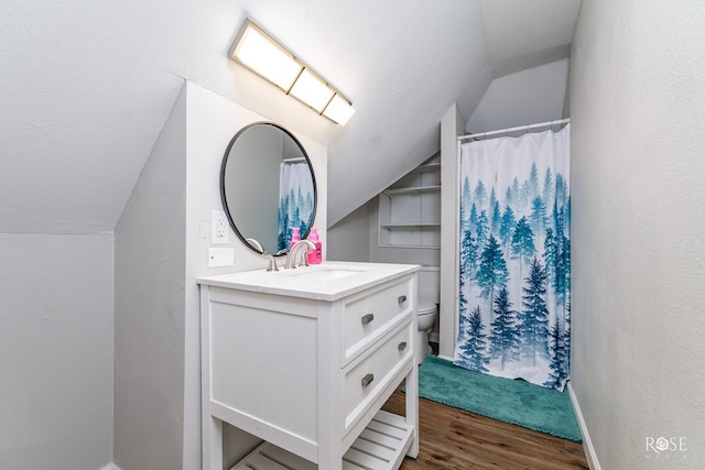 bathroom featuring wood-type flooring, lofted ceiling, vanity, and toilet