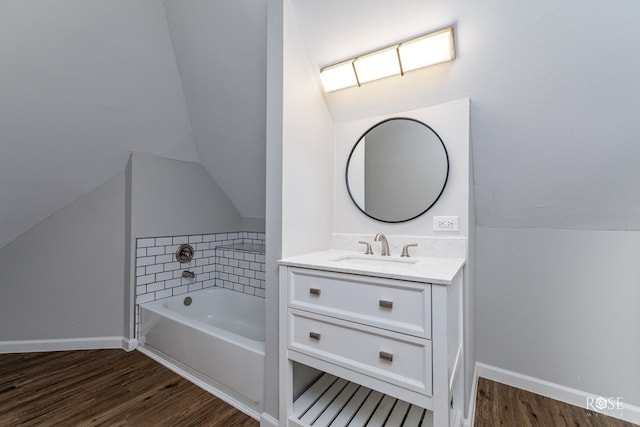 bathroom featuring a bathing tub, vaulted ceiling, wood-type flooring, and vanity