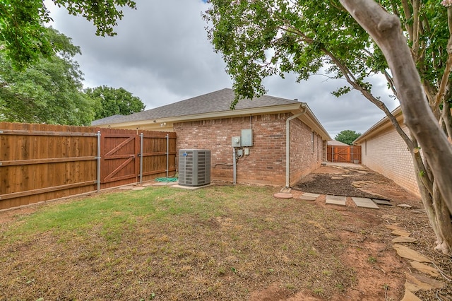 4413 Pinon Ridge Dr, San Angelo, TX 76904 - rear view of house with central air condition unit, a gate, brick siding, and roof with shingles
