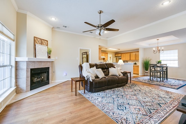 4413 Pinon Ridge Dr, San Angelo, TX 76904 - living room featuring light wood finished floors, ceiling fan, baseboards, a tile fireplace, and ornamental molding