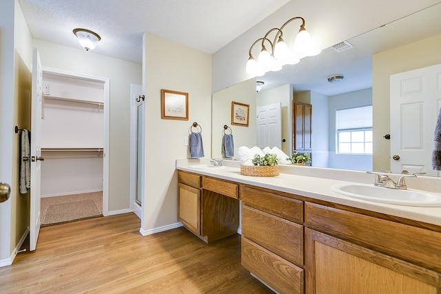 4413 Pinon Ridge Dr, San Angelo, TX 76904 - bathroom featuring double vanity, wood finished floors, a walk in closet, and a shower stall