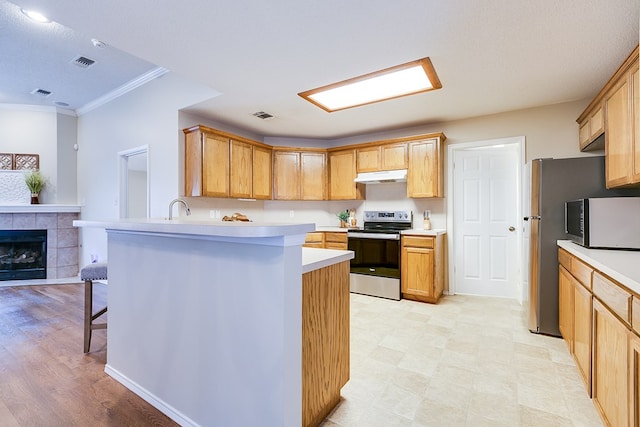 4413 Pinon Ridge Dr, San Angelo, TX 76904 - kitchen with stainless steel range with electric cooktop, under cabinet range hood, light countertops, a peninsula, and a breakfast bar
