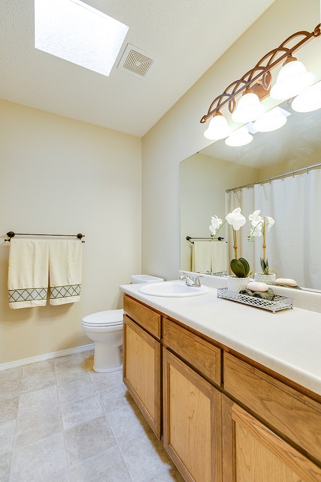 4413 Pinon Ridge Dr, San Angelo, TX 76904 - bathroom featuring vanity, toilet, a skylight, and baseboards