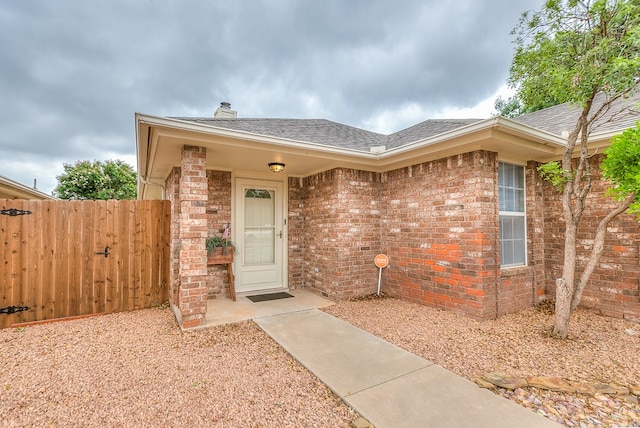 4413 Pinon Ridge Dr, San Angelo, TX 76904 - entrance to property with roof with shingles, brick siding, and a chimney