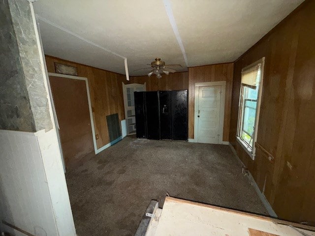 interior space featuring ceiling fan and wood walls