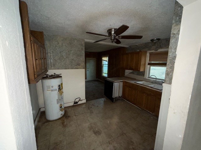 kitchen featuring ceiling fan, sink, water heater, and a textured ceiling