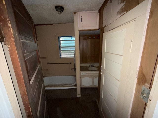 bathroom with sink, a bathtub, and a textured ceiling