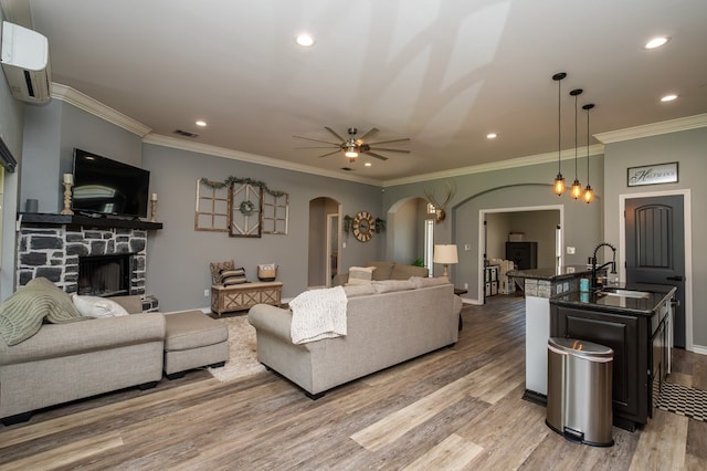 3918 Caroline Ln, San Angelo, TX 76904 - living room featuring arched walkways, light wood-type flooring, a wall unit AC, a fireplace, and crown molding