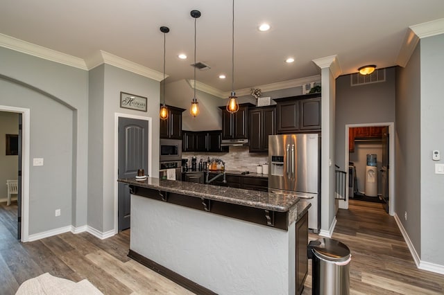 3918 Caroline Ln, San Angelo, TX 76904 - kitchen featuring stainless steel appliances, ornamental molding, dark stone countertops, dark wood-type flooring, and backsplash
