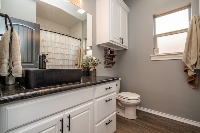 3918 Caroline Ln, San Angelo, TX 76904 - full bathroom with baseboards, wood finished floors, vanity, toilet, and a shower with shower curtain