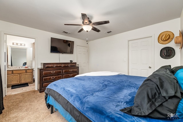 carpeted bedroom with ensuite bath and ceiling fan