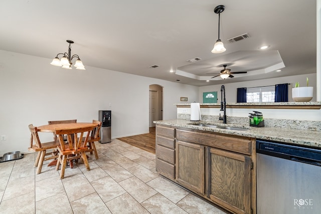 kitchen featuring pendant lighting, sink, dishwasher, light stone countertops, and a raised ceiling