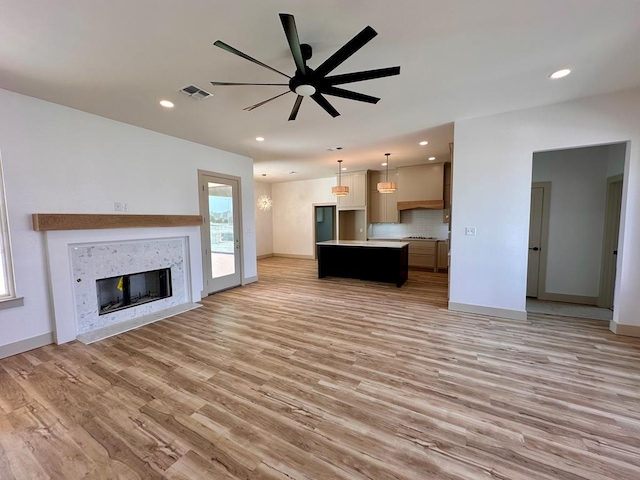 unfurnished living room featuring visible vents, recessed lighting, a fireplace, ceiling fan, and light wood-type flooring