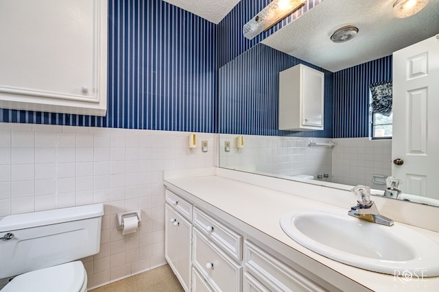3222 Oak Mountain Trl, San Angelo, TX 76904 - bathroom featuring wallpapered walls, tile walls, a textured ceiling, vanity, and wainscoting