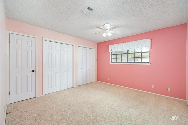 3222 Oak Mountain Trl, San Angelo, TX 76904 - unfurnished bedroom with carpet, multiple closets, a textured ceiling, and ceiling fan