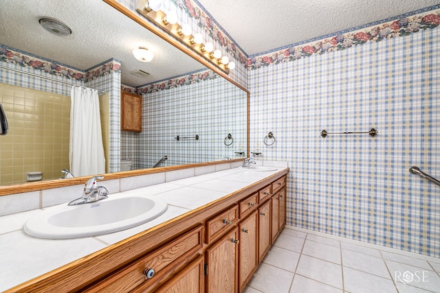 3222 Oak Mountain Trl, San Angelo, TX 76904 - bathroom with a textured ceiling, wallpapered walls, double vanity, tile patterned floors, and a shower with curtain