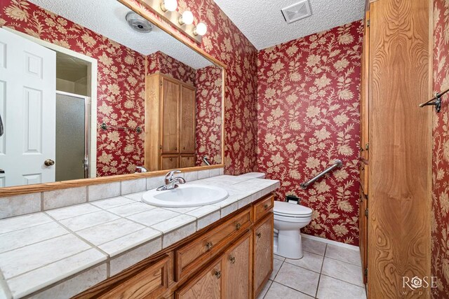 3222 Oak Mountain Trl, San Angelo, TX 76904 - full bathroom with tile patterned floors, wallpapered walls, a textured ceiling, vanity, and a shower stall