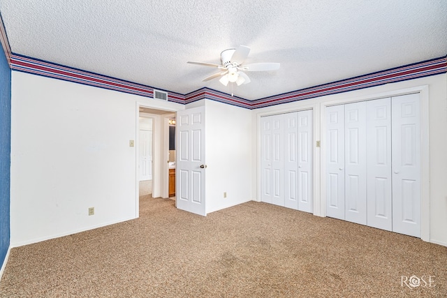 3222 Oak Mountain Trl, San Angelo, TX 76904 - unfurnished bedroom featuring two closets, carpet, a textured ceiling, and ceiling fan