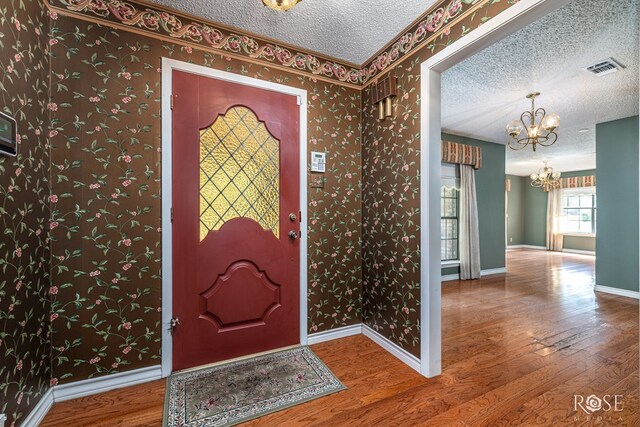 3222 Oak Mountain Trl, San Angelo, TX 76904 - entryway with a chandelier, a textured ceiling, wood finished floors, and wallpapered walls