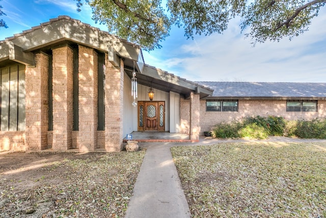 view of exterior entry featuring a shingled roof