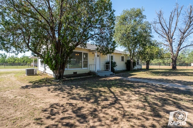 view of front of home with cooling unit and a front yard