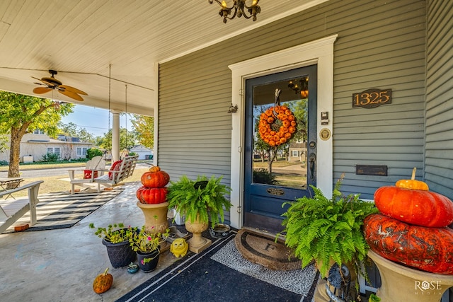 view of exterior entry with ceiling fan and a porch