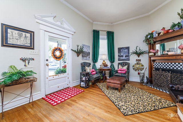 living area featuring crown molding, hardwood / wood-style floors, and a tile fireplace