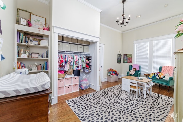 bedroom with crown molding, wood-type flooring, a chandelier, and a closet