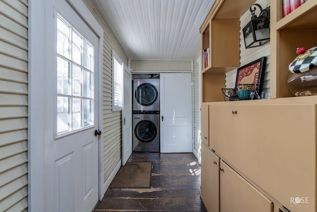 laundry room featuring stacked washer and dryer, a wealth of natural light, and dark hardwood / wood-style floors