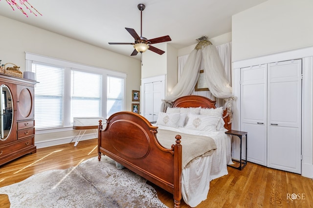 bedroom with multiple closets, ceiling fan, and light wood-type flooring