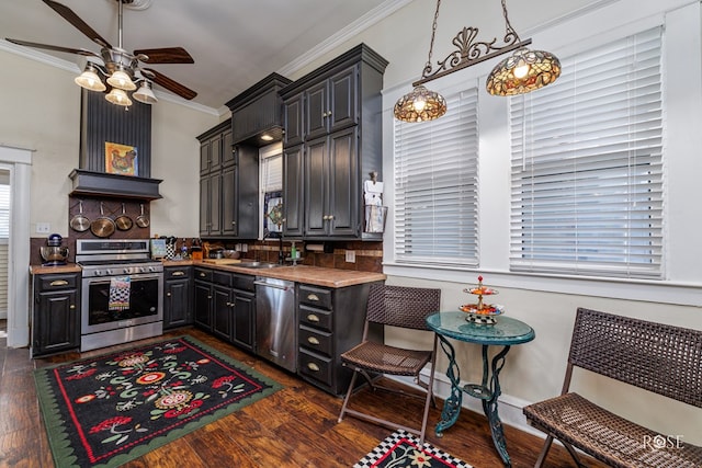 kitchen with sink, hanging light fixtures, ornamental molding, appliances with stainless steel finishes, and dark hardwood / wood-style flooring