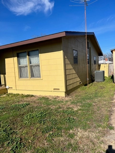 view of side of home featuring cooling unit and a lawn