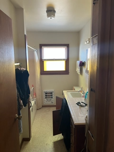 bathroom featuring heating unit, vanity, and shower / tub combo with curtain