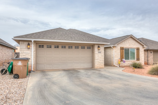 single story home with concrete driveway, a shingled roof, and an attached garage