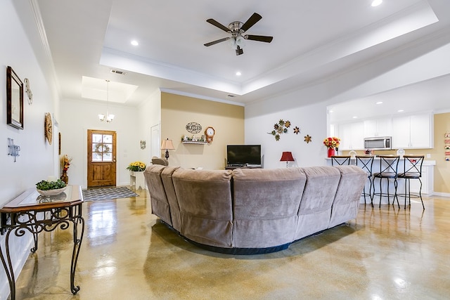 living area with a tray ceiling, recessed lighting, ornamental molding, concrete flooring, and ceiling fan with notable chandelier