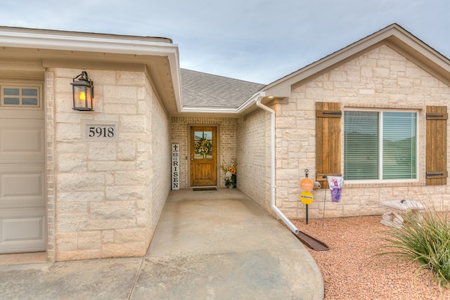 property entrance featuring a shingled roof, stone siding, brick siding, and a garage